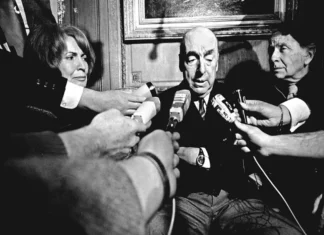 Chile resalta la obra y legado de Pablo Neruda a 122 años de su natalicio Pablo Neruda sentado en su escritorio, rodeado de libros y papeles, simbolizando su legado y obra