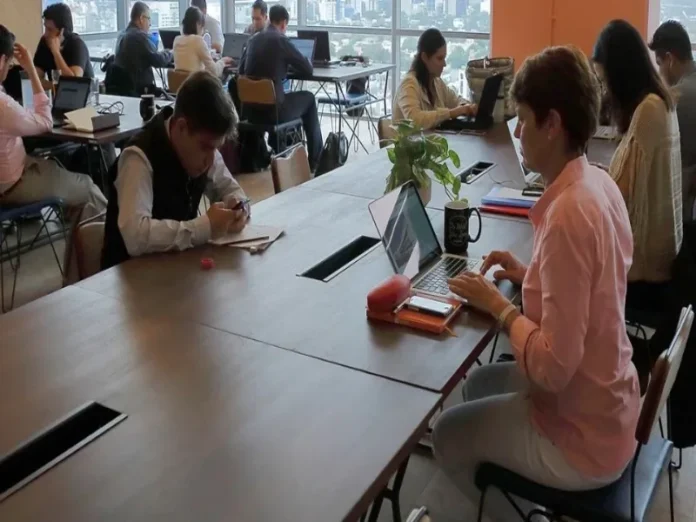 Mujer mexicana en oficina con expresión de incomodidad Mujer mexicana afectada por menopausia laboral en su entorno laboral